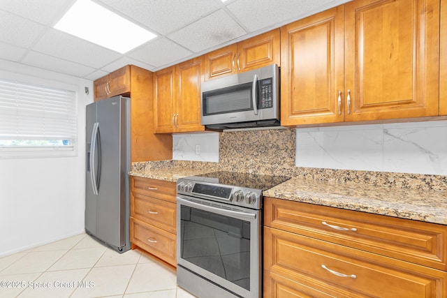 1700 N Atlantic Ave Unit 133, Cocoa Beach, FL 32931 - kitchen with stainless steel appliances, brown cabinets, light stone countertops, and a paneled ceiling