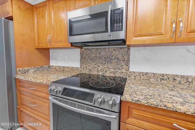 1700 N Atlantic Ave Unit 133, Cocoa Beach, FL 32931 - kitchen with stainless steel appliances, decorative backsplash, light stone countertops, and brown cabinets