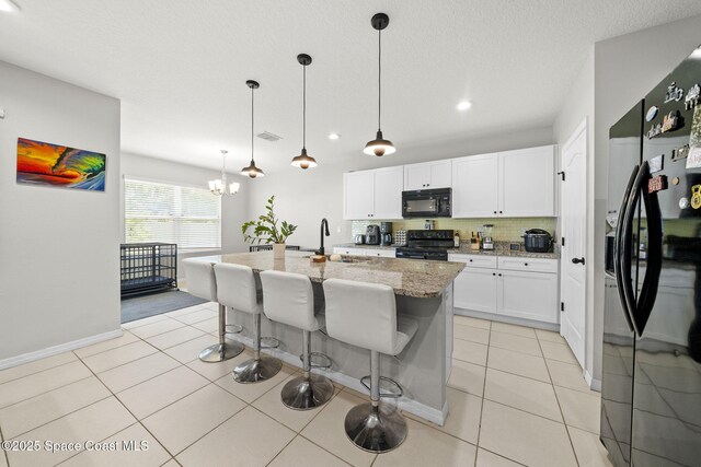 3779 Bishop Landing Way, Orlando, FL 32824 - kitchen featuring black appliances, a sink, light stone counters, tasteful backsplash, and white cabinets