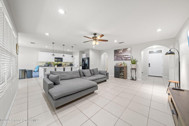 3779 Bishop Landing Way, Orlando, FL 32824 - living room with arched walkways, recessed lighting, baseboards, a ceiling fan, and light tile patterned floors