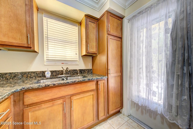 350 Taylor Ave Unit 2B3, Cape Canaveral, FL 32920 - kitchen featuring a sink, brown cabinets, ornamental molding, dark stone counters, and light tile patterned flooring