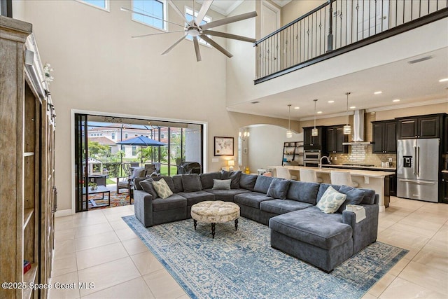 2228 Zuma Ln, Melbourne, FL 32940 - living area featuring arched walkways, a towering ceiling, ceiling fan, light tile patterned flooring, and crown molding