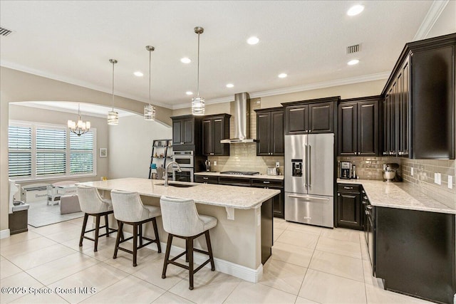 2228 Zuma Ln, Melbourne, FL 32940 - kitchen with stainless steel appliances, wall chimney exhaust hood, a chandelier, a breakfast bar area, and tasteful backsplash