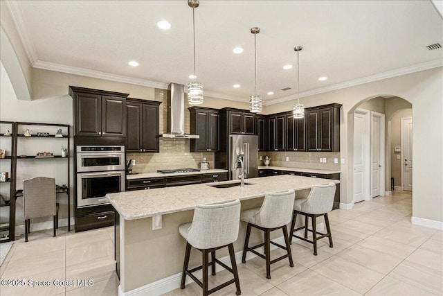 2228 Zuma Ln, Melbourne, FL 32940 - kitchen with wall chimney range hood, arched walkways, stainless steel appliances, a kitchen island with sink, and backsplash