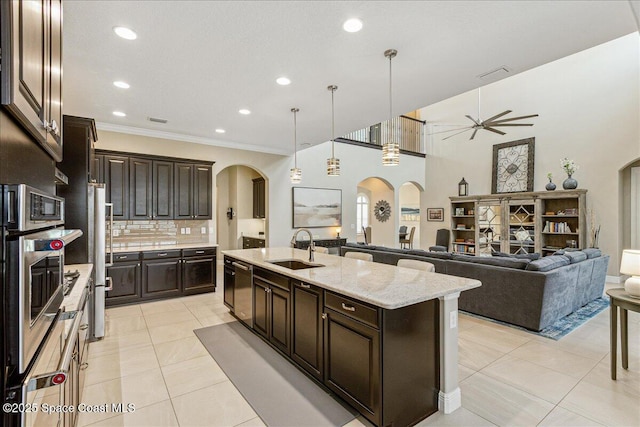 2228 Zuma Ln, Melbourne, FL 32940 - kitchen featuring arched walkways, a ceiling fan, ornamental molding, a kitchen island with sink, and backsplash
