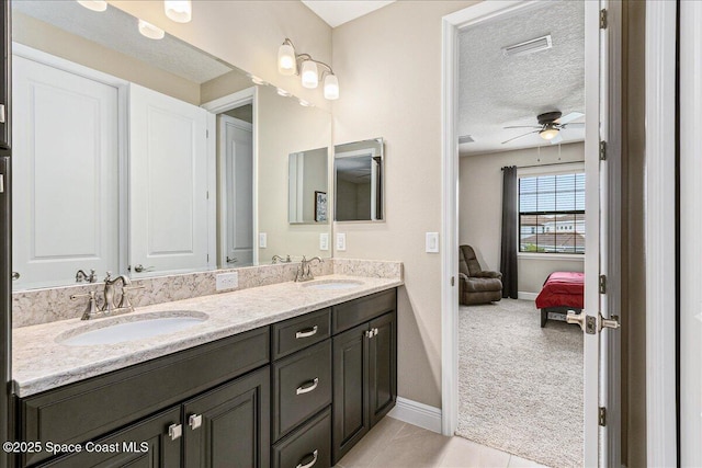 2228 Zuma Ln, Melbourne, FL 32940 - bathroom with double vanity, a ceiling fan, connected bathroom, and a textured ceiling
