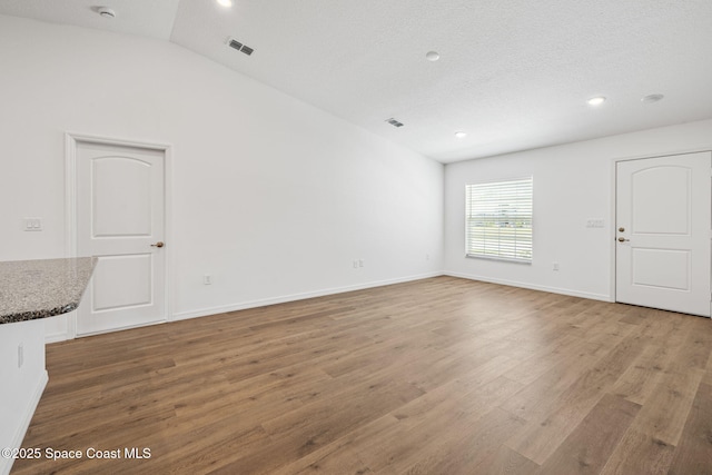 1650 Wyoming Dr SE, Palm Bay, FL 32909 - unfurnished living room featuring light wood-type flooring, recessed lighting, lofted ceiling, and baseboards