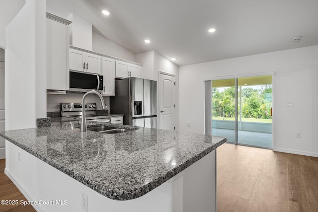 1650 Wyoming Dr SE, Palm Bay, FL 32909 - kitchen featuring appliances with stainless steel finishes, wood finished floors, dark stone counters, a sink, and recessed lighting