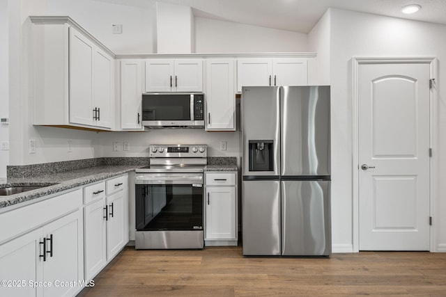 1650 Wyoming Dr SE, Palm Bay, FL 32909 - kitchen featuring appliances with stainless steel finishes, vaulted ceiling, white cabinets, light wood finished floors, and recessed lighting