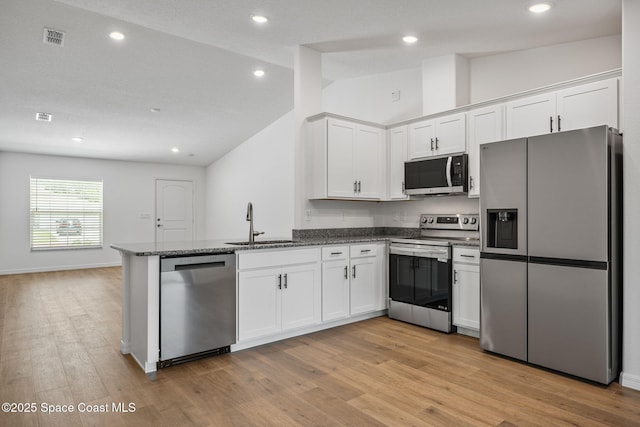 1650 Wyoming Dr SE, Palm Bay, FL 32909 - kitchen featuring stainless steel appliances, a sink, vaulted ceiling, a peninsula, and white cabinetry