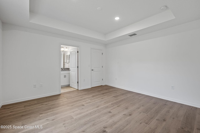 1650 Wyoming Dr SE, Palm Bay, FL 32909 - unfurnished bedroom with a tray ceiling, baseboards, recessed lighting, and light wood-style floors