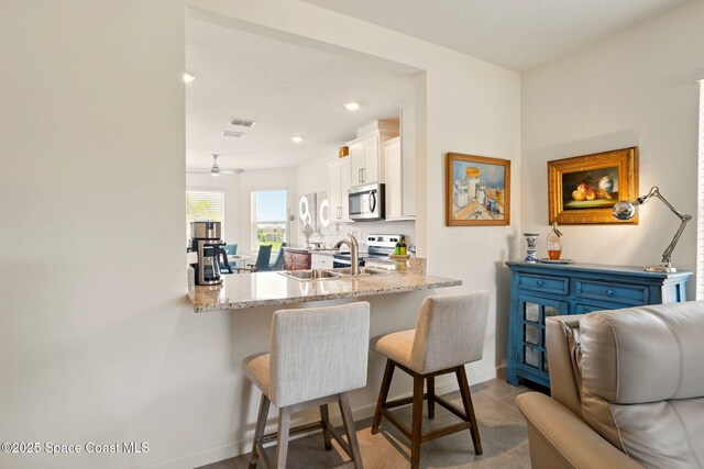 3547 Aberdeen Dr SE, Palm Bay, FL 32909 - kitchen featuring appliances with stainless steel finishes, a kitchen bar, white cabinetry, a sink, and a peninsula