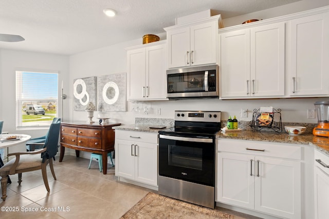3547 Aberdeen Dr SE, Palm Bay, FL 32909 - kitchen featuring stainless steel appliances, white cabinets, light stone countertops, light tile patterned floors, and a textured ceiling