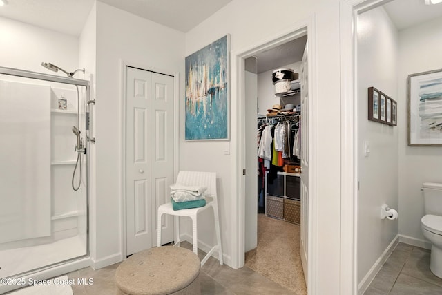 3547 Aberdeen Dr SE, Palm Bay, FL 32909 - bathroom featuring a stall shower, toilet, tile patterned flooring, a walk in closet, and baseboards