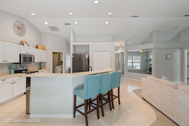 4070 Orion Way, Rockledge, FL 32955 - kitchen featuring appliances with stainless steel finishes, light tile patterned flooring, open floor plan, high vaulted ceiling, and white cabinetry