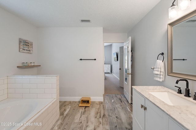 4070 Orion Way, Rockledge, FL 32955 - bathroom featuring vanity, wood finished floors, a garden tub, and baseboards