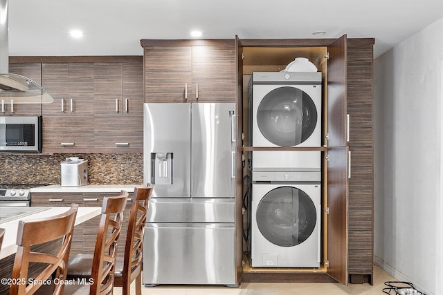 253 NE 212th Ter, Miami, FL 33177 - kitchen with stainless steel appliances, estacked washer and dryer, decorative backsplash, and light countertops