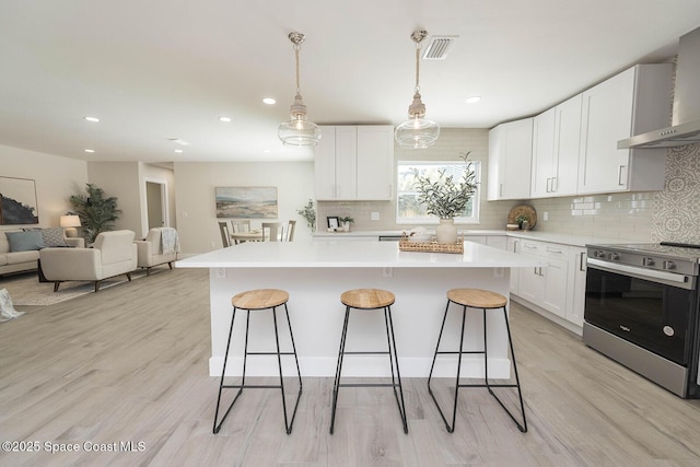 3201 Nottingham Ln, Cocoa, FL 32926 - kitchen with electric range, wall chimney exhaust hood, a breakfast bar area, decorative backsplash, and a kitchen island