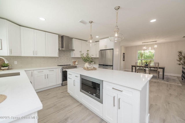 3201 Nottingham Ln, Cocoa, FL 32926 - kitchen featuring stainless steel appliances, wall chimney exhaust hood, backsplash, light wood-style flooring, and recessed lighting