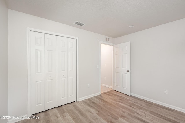 1094 Locust Ave NW, Palm Bay, FL 32907 - unfurnished bedroom with light wood-style flooring, baseboards, a closet, and a textured ceiling