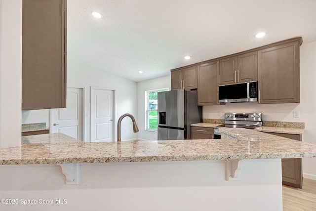 2597 Galiano Ave, Palm Bay, FL 32908 - kitchen featuring appliances with stainless steel finishes, a kitchen bar, light stone counters, recessed lighting, and a textured ceiling