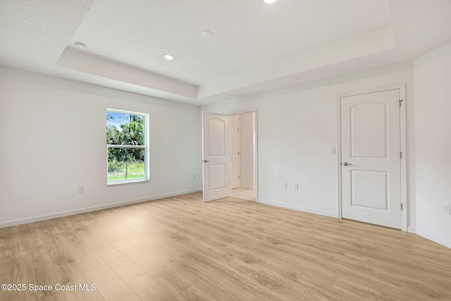 2597 Galiano Ave, Palm Bay, FL 32908 - unfurnished bedroom featuring a tray ceiling, light wood-type flooring, baseboards, recessed lighting, and a textured ceiling