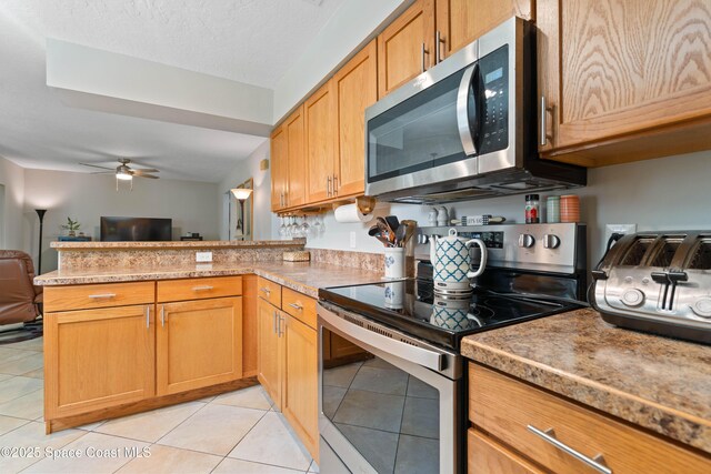 1250 York Cir, Melbourne, FL 32904 - kitchen featuring stainless steel appliances, a peninsula, a ceiling fan, open floor plan, and light tile patterned floors