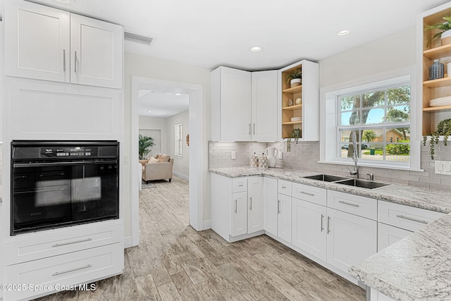 520 Bahama Dr, Indian Harbour Beach, FL 32937 - kitchen with black oven, open shelves, a sink, white cabinets, and backsplash