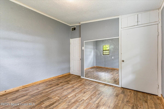 2835 Sunset Rd, Melbourne, FL 32904 - unfurnished bedroom with wood finished floors, a textured wall, a textured ceiling, crown molding, and a closet