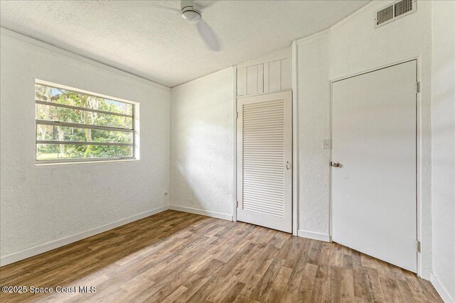 2835 Sunset Rd, Melbourne, FL 32904 - unfurnished bedroom featuring wood finished floors, a textured ceiling, a textured wall, baseboards, and ceiling fan