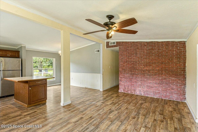 2835 Sunset Rd, Melbourne, FL 32904 - unfurnished living room featuring ornamental molding, a ceiling fan, wood finished floors, brick wall, and a textured ceiling