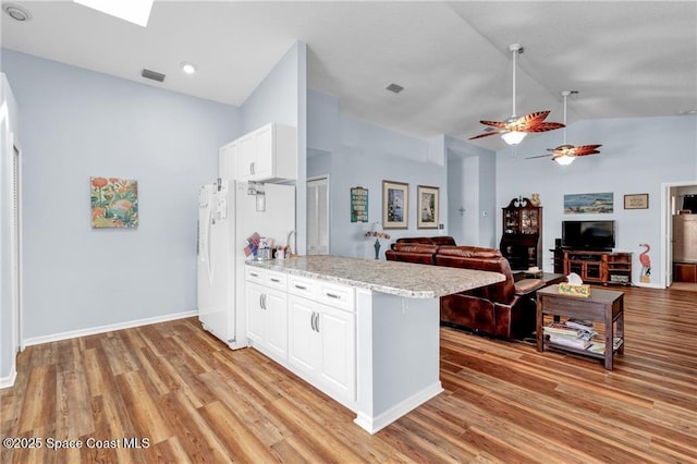 749 Tulip Dr, Sebastian, FL 32958 - kitchen featuring freestanding refrigerator, vaulted ceiling, light wood-style flooring, white cabinets, and a peninsula
