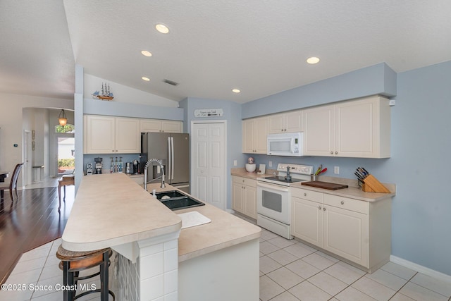 2020 Twelve Oaks Dr SE, Palm Bay, FL 32909 - kitchen featuring white appliances, a sink, light countertops, a kitchen breakfast bar, and lofted ceiling
