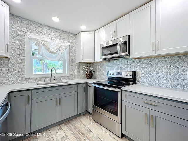 201 Woody Cir, Melbourne Beach, FL 32951 - kitchen featuring stainless steel appliances, a sink, gray cabinets, light wood-style floors, and tasteful backsplash