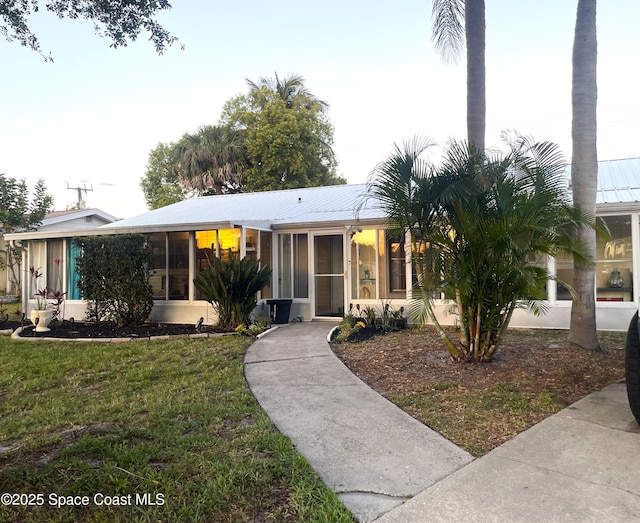 610 Buttonwood Dr, Merritt Island, FL 32953 - ranch-style home featuring a sunroom, a front lawn, and metal roof