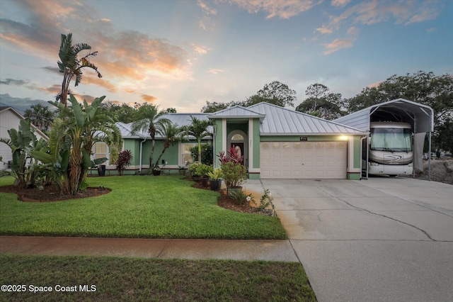 4625 Curtis Blvd, Cocoa, FL 32927 - view of front of home featuring metal roof, driveway, a carport, an attached garage, and a lawn