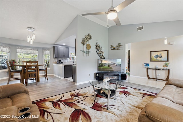 4625 Curtis Blvd, Cocoa, FL 32927 - living room with light wood finished floors, ceiling fan, high vaulted ceiling, baseboards, and a chandelier