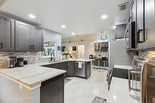 4625 Curtis Blvd, Cocoa, FL 32927 - kitchen featuring a peninsula, a sink, stainless steel appliances, backsplash, and light tile patterned flooring