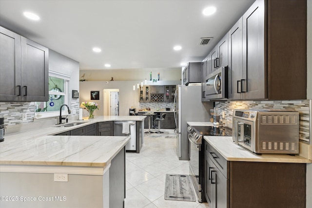 4625 Curtis Blvd, Cocoa, FL 32927 - kitchen featuring appliances with stainless steel finishes, a sink, a peninsula, tasteful backsplash, and light stone countertops