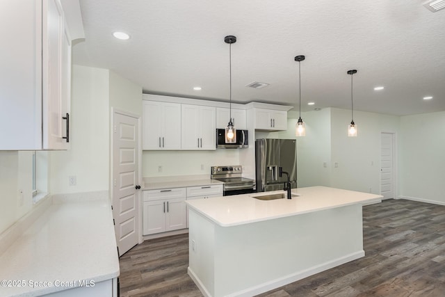 123 Garylind St SW, Palm Bay, FL 32908 - kitchen with stainless steel appliances, a sink, dark wood-style flooring, white cabinetry, and an island with sink