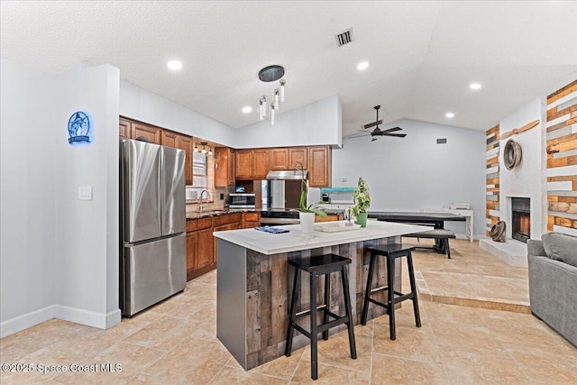 2350 Fallon Blvd NE, Palm Bay, FL 32907 - kitchen with appliances with stainless steel finishes, lofted ceiling, brown cabinetry, ceiling fan, and a kitchen bar