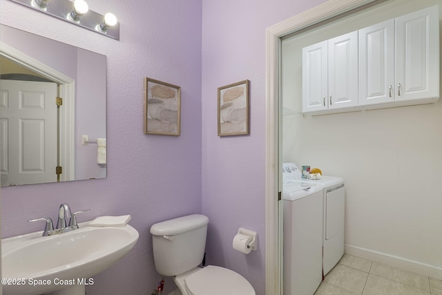 7961 Evelyn Ct, Cape Canaveral, FL 32920 - bathroom featuring washing machine and clothes dryer, a sink, tile patterned flooring, toilet, and baseboards