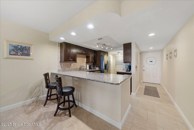 4100 Ocean Beach Blvd Unit 210, Cocoa Beach, FL 32931 - kitchen with stainless steel fridge with ice dispenser, a peninsula, dark brown cabinetry, a breakfast bar, and tasteful backsplash