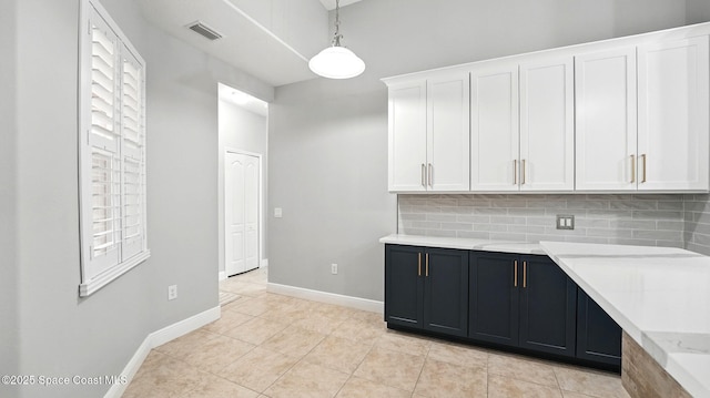 5852 Goleta Cir, Melbourne, FL 32940 - kitchen with white cabinets, decorative light fixtures, decorative backsplash, baseboards, and light tile patterned floors