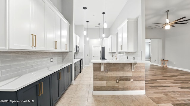 5852 Goleta Cir, Melbourne, FL 32940 - kitchen with appliances with stainless steel finishes, ceiling fan, white cabinetry, decorative backsplash, and a breakfast bar