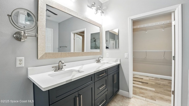 5852 Goleta Cir, Melbourne, FL 32940 - bathroom with double vanity, a walk in closet, and baseboards