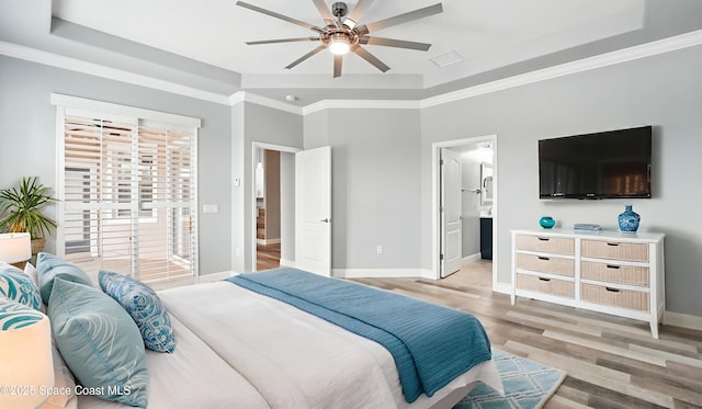 5852 Goleta Cir, Melbourne, FL 32940 - bedroom with a tray ceiling, light wood-style flooring, baseboards, ornamental molding, and connected bathroom