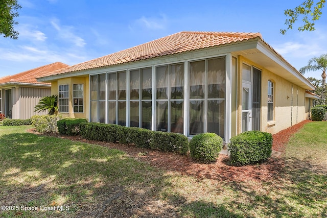 8051 Daventry Dr, Melbourne, FL 32940 - view of home's exterior with a tiled roof, a sunroom, stucco siding, and a yard