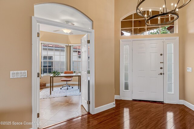 8051 Daventry Dr, Melbourne, FL 32940 - foyer entrance with baseboards, a chandelier, wood finished floors, a ceiling fan, and a towering ceiling