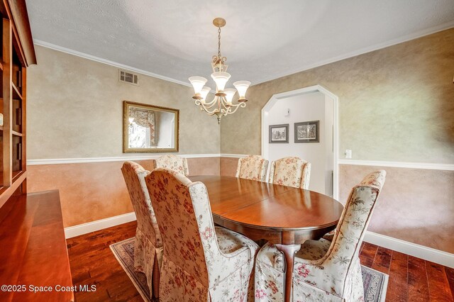 2280 Grove St, Titusville, FL 32796 - dining area featuring wood finished floors, a chandelier, crown molding, baseboards, and arched walkways